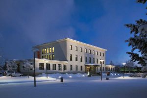 There is snow on the ground in front of the illuminated Museum Gustaf and a dark blue winter sky in the background.
