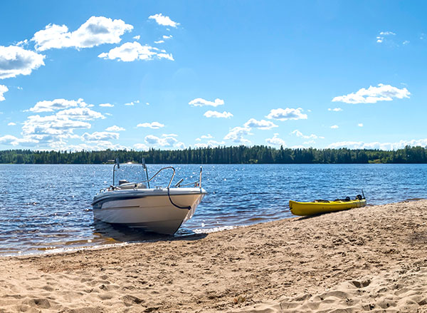 A motorboat and a kayak at the shore on a summer day.