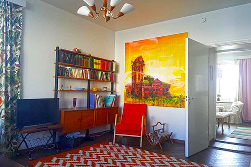 The licing room of Pinecastle apartment. Red chair in the middle and behid it a bright yellow toned painting
