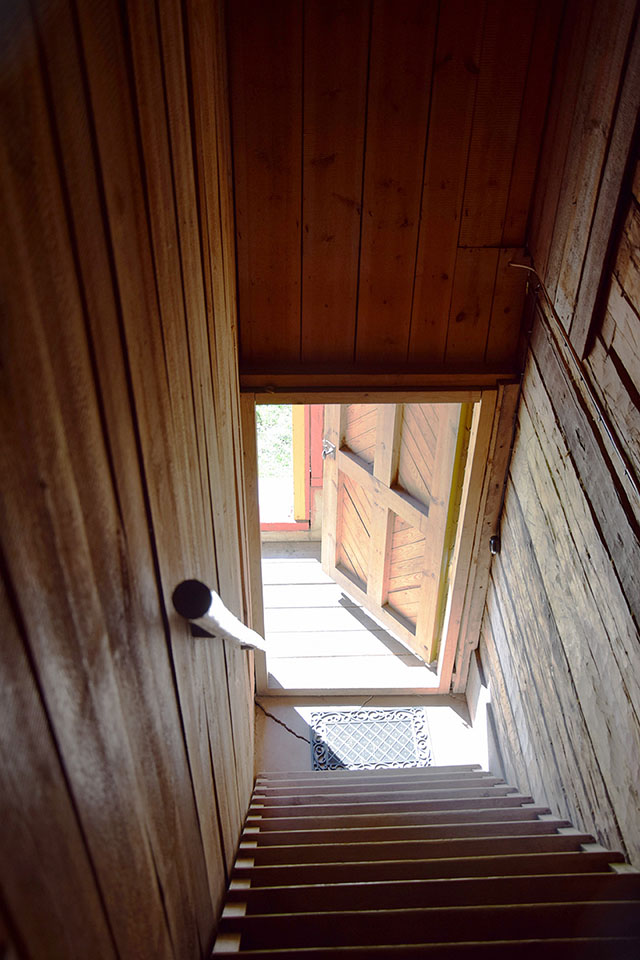Salustaipaleen tilan rappukäytävä ylhäältä päin kuvattuna, alhaalla näkyy avoin ovi josta tulee auringonvaloa sisään.