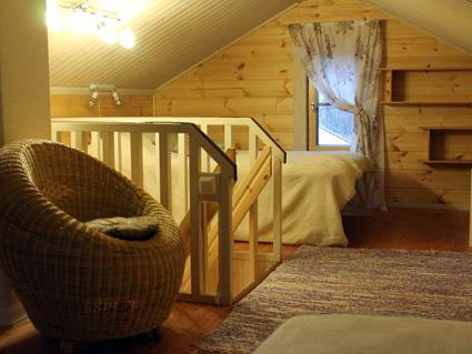 The upstairs area of the cabin, with a rattan chair and a nicely made bed.