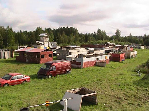A paintball arena featuring various obstacles and vehicles.