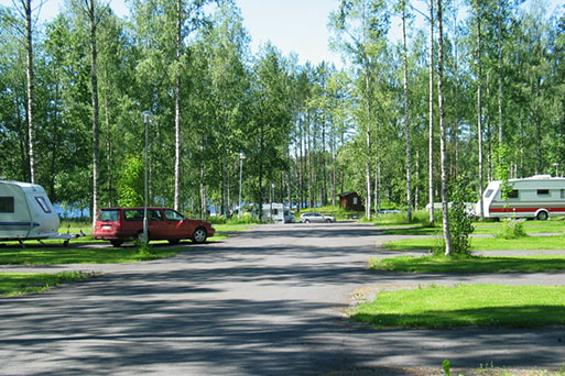 Caravan-alue, autoja ja asuntovaunuja vehreässä puistikossa.