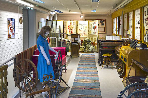 Perinnehuoneen näyttelytila, jossa esillä vanhoja esineitä, muun muassa rukki, harmooni ja seinillä vanhoja koulutauluja