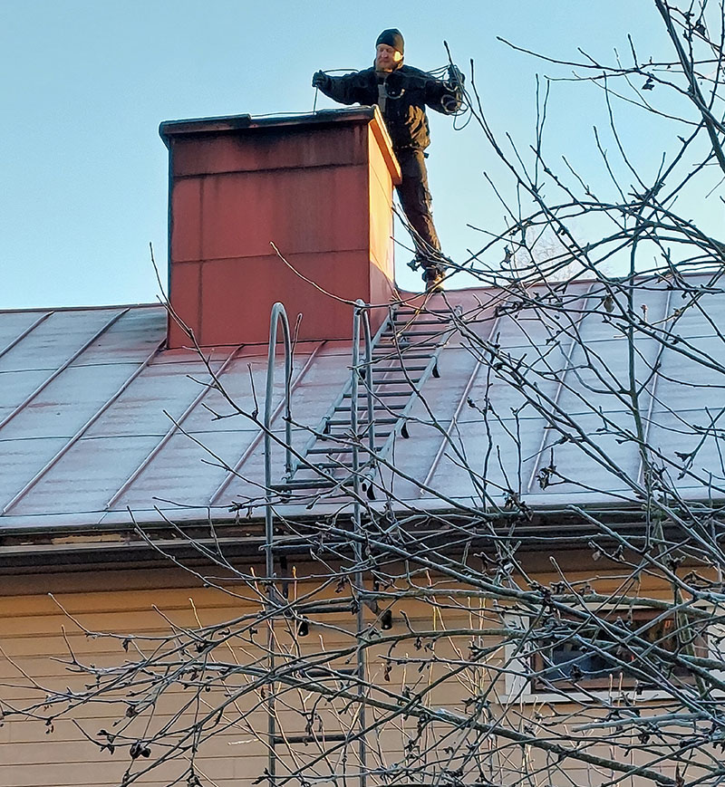 Nuohouspalvelu Hietala katolla nuohoamassa savupiippua.