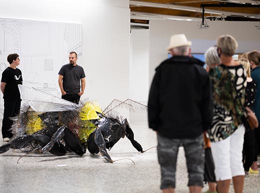 A group of people is looking at a giant bee-sculpture.